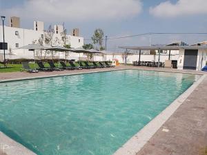 a large swimming pool with chairs and umbrellas at Amplia casa equipada para familia, pareja o individual in Tizayuca