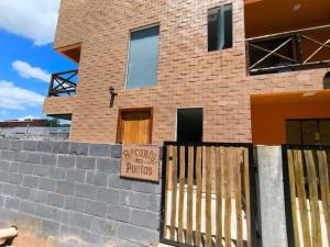 a brick house with a sign on a fence at Suíte Recanto dos poetas 07 in Lençóis
