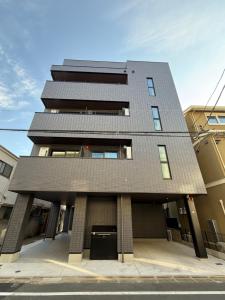 a tall building with a black roof on a street at PRISM Inn Ikegami Kamata in Tokyo
