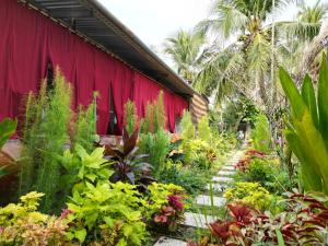a garden with colorful flowers and a red curtain at Comfy room - InnerZen Mekong Riverside homestay Ben Tre in Ben Tre +76 photos