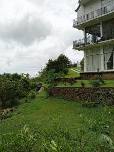 a house on a grassy hill next to a building at Tranquil Edge Villa in Haputale