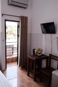 a room with a table and a television on a wall at 5H homestay & Motorbikes For Rent in Hue