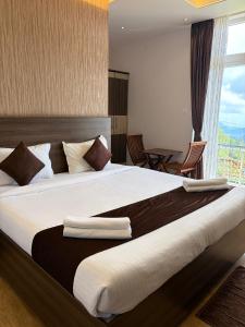 a bedroom with a large bed with a window at Vanam Holidays in Ooty