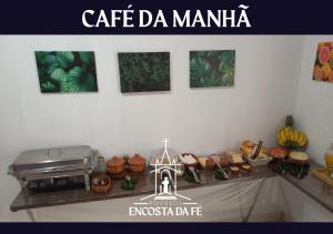 a counter top with a table with food and pictures at Pousada Encosta da Fé - Unidade Centro in Juazeiro do Norte