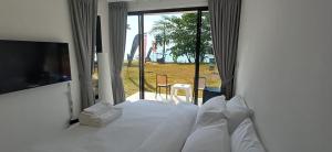 a bedroom with a white bed with a large window at Sunrise Beachfront Rawai in Ban Saiyuan (1)