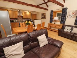 a living room with a leather couch and a kitchen at Stable D'or in Alnwick