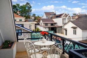 a table with chairs and a vase of flowers on a balcony at Lumi Home Đà Lạt in Da Thanh