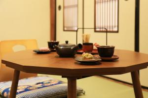 a wooden table with bowls and cups on it at Kimono Hotel Himeji 着物宿 in Himeji