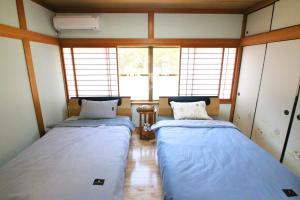 two beds sitting in a room with windows at 蝶自来 in Yamaga