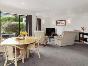 a living room with a table and chairs and a television at 3 bedroom home Tranquil Views in Rotorua