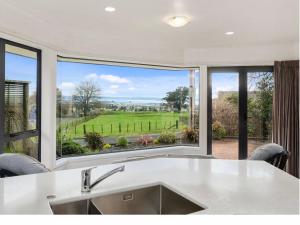 a kitchen with a large window overlooking a green field at 3 bedroom home Tranquil Views in Rotorua