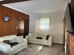 a living room with two white couches and a tv at Beach house in Hallidays Point