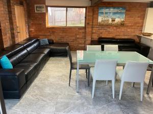a living room with a leather couch and a table at Beach house in Hallidays Point