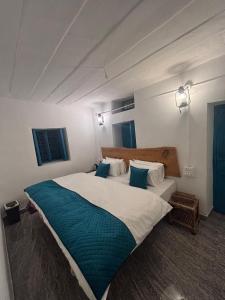 a bedroom with a large bed with blue pillows at NAMOH e VIRAASAT in Chopta +14 photos