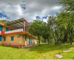 a house in a field with trees in the background at NAMOH e VIRAASAT in Chopta