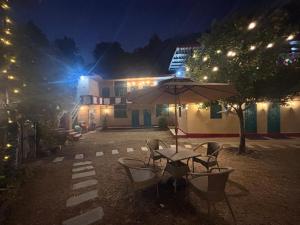 a table and chairs with an umbrella in front of a building at NAMOH e VIRAASAT in Chopta