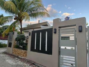 a house with a gate and a palm tree at Shella Home Stay in Miagao