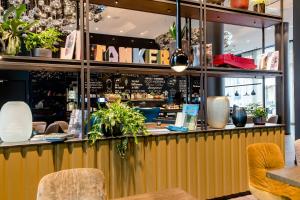 a restaurant with a yellow counter with plants at Motel One Köln-Altstadt in Cologne