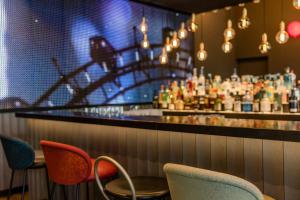 a bar with chairs and a counter with a drink at Motel One Wien-Prater in Vienna