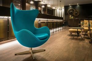 a blue chair in a room with tables and chairs at Motel One Newcastle in Newcastle upon Tyne