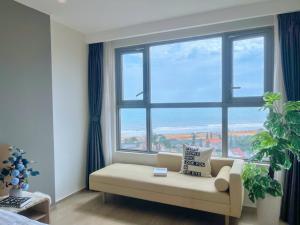a living room with a couch and a large window at Căn hô The Song Du lịch Biển Tháp Tam Thắng Infinity Pool - Sophia Home in Vung Tau