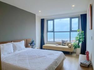 a bedroom with a bed and a couch and a window at Căn hô The Song Du lịch Biển Tháp Tam Thắng Infinity Pool - Sophia Home in Vung Tau