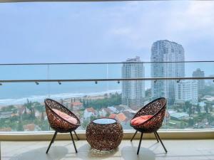 two chairs sitting in front of a large window at Căn hô The Song Du lịch Biển Tháp Tam Thắng Infinity Pool - Sophia Home in Vung Tau
