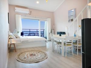 a bedroom with a bed and a table and a dining room at Pension Haneul Tari in Jeju