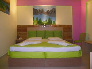 Un dormitorio con una cama verde con una pintura en la pared en Mirabelle Hotel en Argasio