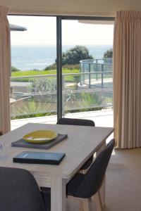 mesa de comedor con vistas al océano en The Reef Beachfront Apartments, en Mount Maunganui
