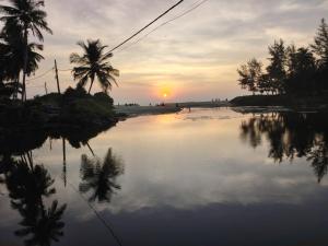 a sunset over a body of water with palm trees at Pratheeksha Homestay in Kannur +5 photos