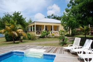 une maison avec une piscine et des chaises sur une terrasse dans l'établissement Yepton Estate Cottages, à Saint Johnʼs