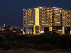a hotel with a lit up building at night at Mercure Muscat in Muscat