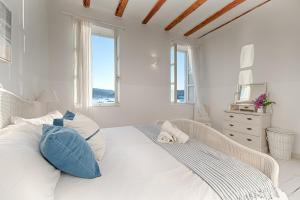 ein weißes Schlafzimmer mit einem Bett mit blau-weißen Kissen in der Unterkunft Villa Riva, Vis in Vis