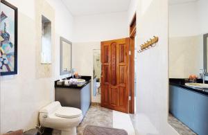 baño con aseo y lavabo y puerta de madera en Villa Buah, en Senggigi 