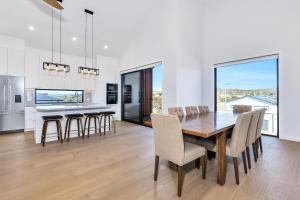 a kitchen and dining room with a wooden table and chairs at Rawson Retreat - Spa, EV outlet and Premium Luxury in Jindabyne