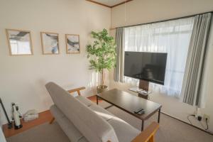 a living room with a couch and a flat screen tv at REKADO ROOM Kengun in Kumamoto