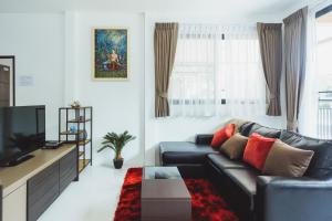 a living room with a black leather couch and a tv at Baan Nern Khao Resort Pattaya in Ban Huai Yai