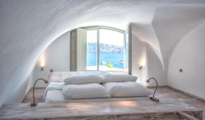 uma cama num quarto com uma grande janela em La Perla Villas and Suites - Adults Only em Oia