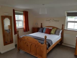 a bedroom with a wooden bed and two windows at The Annexe in Timsbury