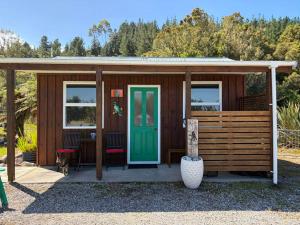 a small wooden cabin with a green door at Sunset Accommodation in Westport