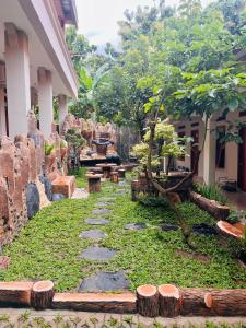 ein Garten mit Steinweg, Bäumen und Bänken in der Unterkunft Arga Hostelry in Kareo