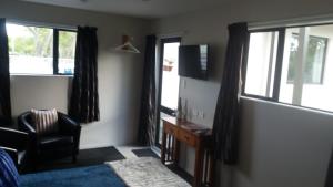 a bedroom with a bed and a chair and windows at Stream View in Christchurch