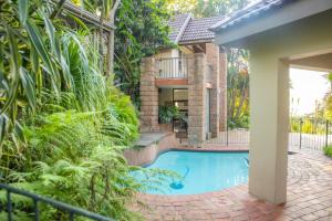 a swimming pool in front of a house with plants at Black n Whyt Villa in Kloof