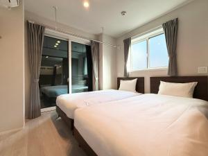 two beds in a bedroom with a window at PRISM Inn Ikegami Kamata in Tokyo