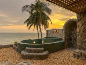 a resort with a palm tree and the ocean at Anket De' River Mui Ne resort in Mui Ne