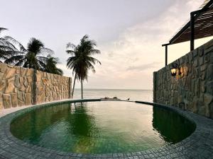 a swimming pool next to the ocean with palm trees at Anket De' River Mui Ne resort in Mui Ne +20 photos