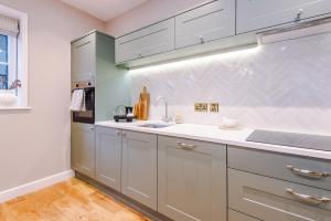 a kitchen with white cabinets and a sink at Cathedral Mews - Close to the Cathedral in Ripon
