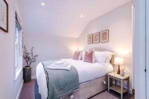 a bedroom with a bed with white sheets and pillows at Cathedral Mews - Close to the Cathedral in Ripon
