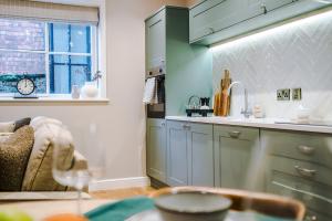 a kitchen with blue cabinets and a window and a couch at Cathedral Mews - Close to the Cathedral in Ripon